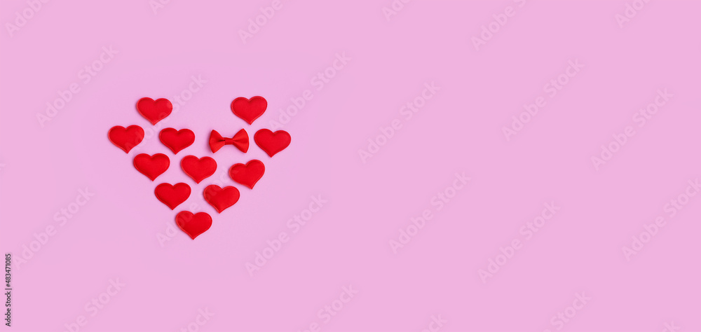 Small red hearts fold into a big heart shape on a pink background. View from above. copy space