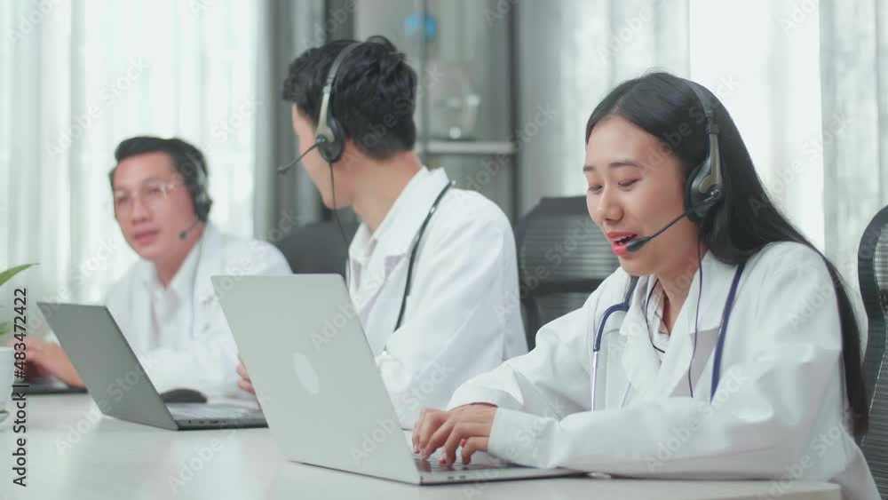 A Woman Of Three Asian Doctors With Stethoscope In Headset Working As Call Center Agents Speaking To Customers On The Call And Typing While Her Colleagues Are Talking During Working At The Office
A Woman Of Three Asian Doctors With Stethoscope In Headset Working As Call Center Agents Speaking To Customers On The Call And Typing While Her Colleagues Are Talking During Working At The Office