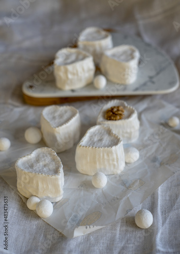 Heart-shaped cheese with white mold on wrapping paper. Home production, natural products.