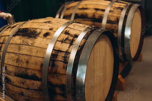 Wooden beer or wine barrels with iron rings in the cellar. Modern Factory. Brewery. Rows of wine barrels in an aging cellar