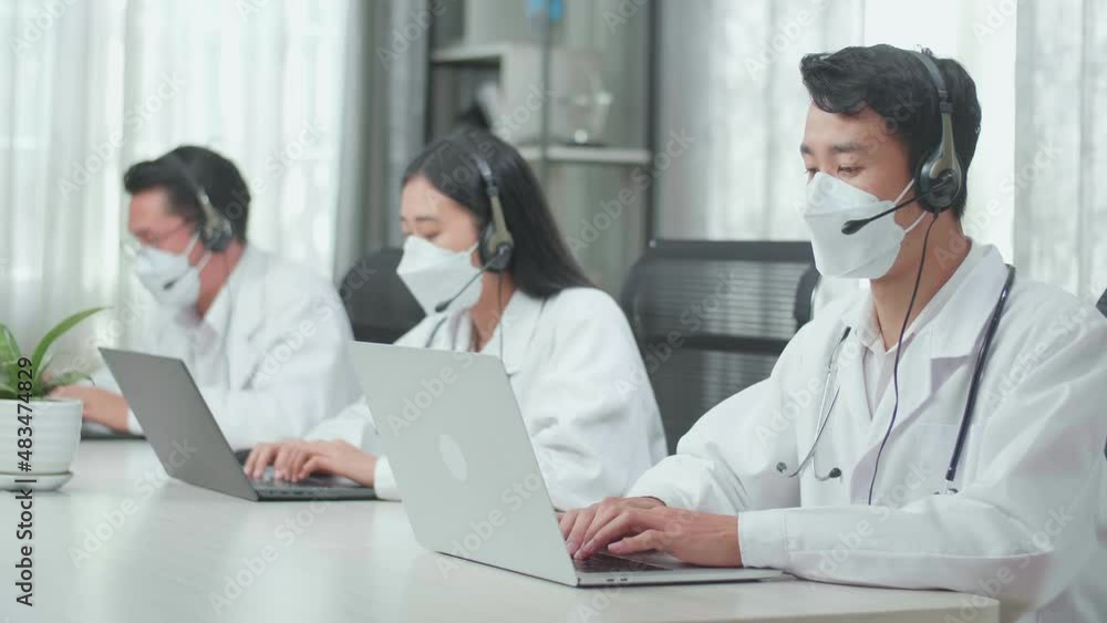 Three Asian Doctors With Stethoscopes Wearing Headsets And Masks Working As Call Center Agents Sitting On Chairs And Typing While Speaking To Customers On The Call At The Office
Three Asian Doctors With Stethoscopes Wearing Headsets And Masks Working As Call Center Agents Sitting On Chairs And Typing While Speaking To Customers On The Call At The Office