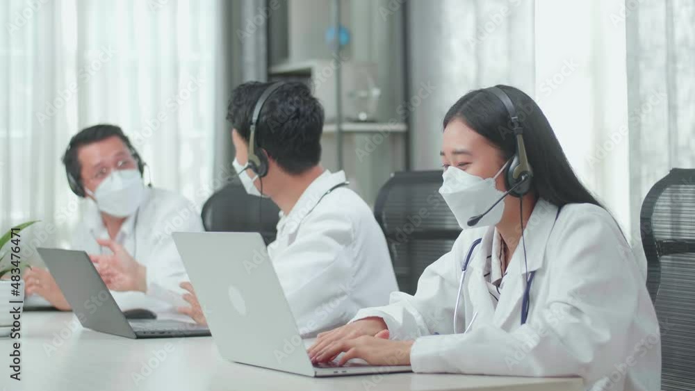 A Woman Of Three Asian Doctors With Stethoscope In Headset And Mask Working As Call Center Agents Speaking On A Call And Typing While Her Colleagues Are Talking During Working At The Office
A Woman Of Three Asian Doctors With Stethoscope In Headset And Mask Working As Call Center Agents Speaking On A Call And Typing While Her Colleagues Are Talking During Working At The Office