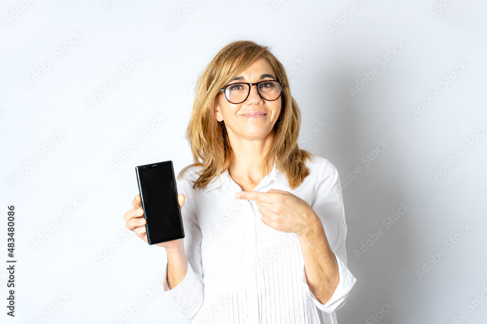 Woman in front on white background shows her mobile phone. Woman in front on white background shows her mobile phone.