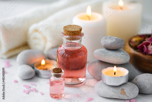 Concept of spa treatment in salon. Natural organic oil, towel, candles as decor. Atmosphere of relax, serenity and pleasure. Anti-stress and detox procedure. Luxury lifestyle. White wooden background