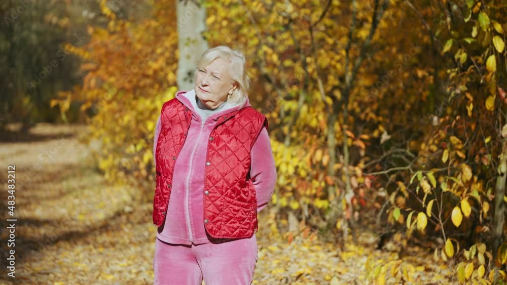 Tired senior woman enjoying warm sunlight in autumn park, resting after exercise Tired senior woman enjoying warm sunlight in autumn park, resting after exercise