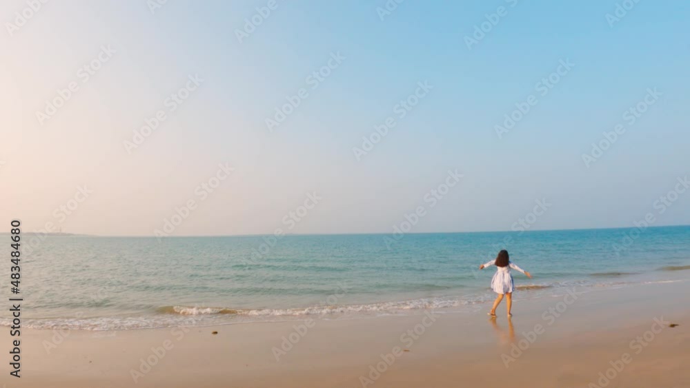 Beautiful landscape of tropical beach with one Indian woman with open arms walking to the sea. Happy traveler woman in white dress enjoys her tropical beach vacation Beautiful landscape of tropical beach with one Indian woman with open arms walking to the sea. Happy traveler woman in white dress enjoys her tropical beach vacation