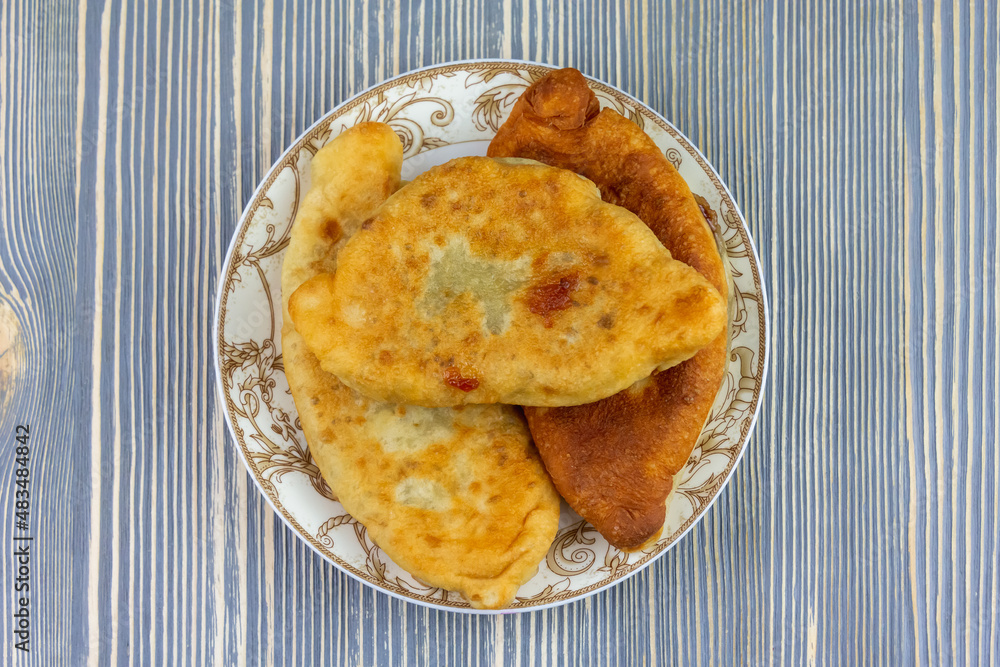 Fried pies in a plate on a wooden table. Fried pies in a plate on a wooden table.