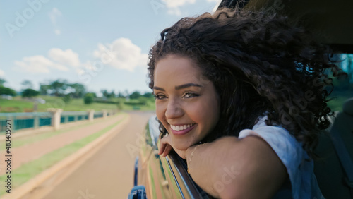 Latin woman in car window. Car trip. Curly hair in wind. Girl looks out of car window. photo