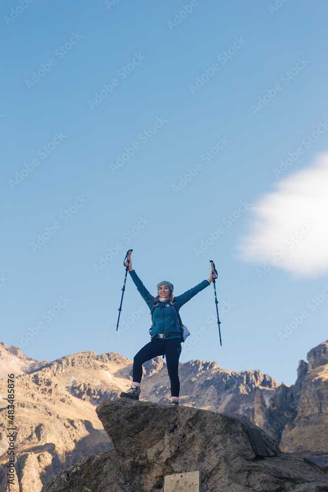 woman with trekking poles standing on the top of the mountain