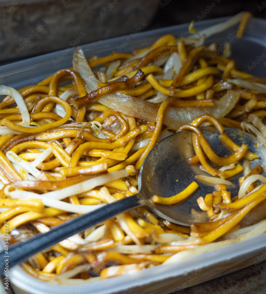 Close and selective focus on a plastic tub of plain chow mein or noodle, onion and beansprouts bought from a Chinese takeout with intentional shallow depth of field and bokeh Close and selective focus on a plastic tub of plain chow mein or noodle, onion and beansprouts bought from a Chinese takeout with intentional shallow depth of field and bokeh