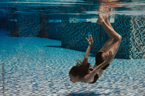 young woman swimming under the water in the pool