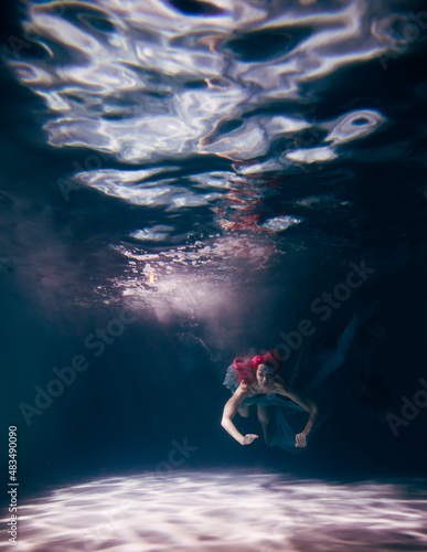 Young woman underwater in a beautiful dress underwater shooting