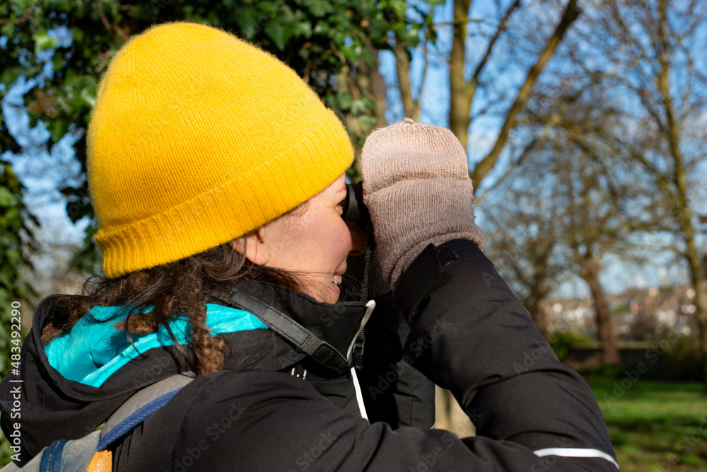 Person with hat and gloves birdwatching on a sunny winter day in nature Person with hat and gloves birdwatching on a sunny winter day in nature