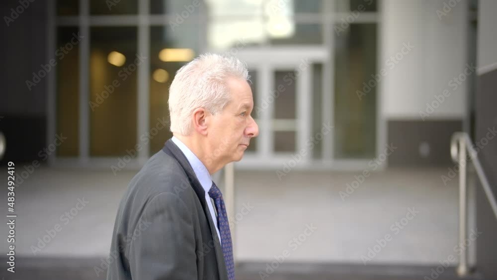 Side view of a businessman walking by office buildings in the city Side view of a businessman walking by office buildings in the city