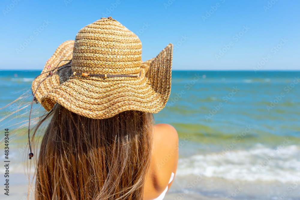 Summer, beautiful little girl in a straw hat is resting on the beach sea