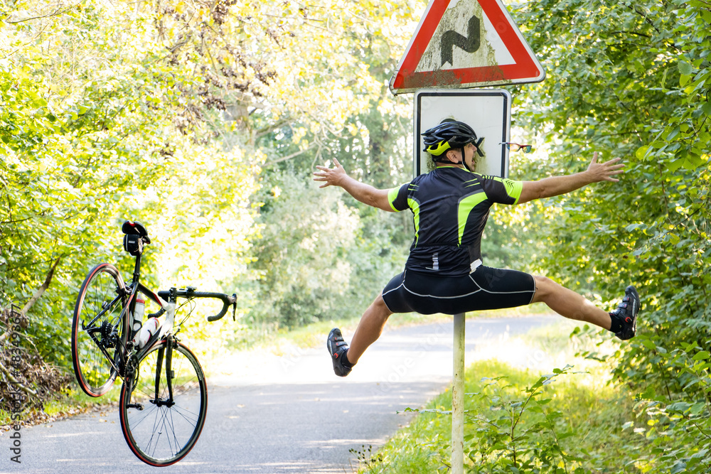 A falling cyclist bumps into a road sign warning about road with turns. - obrazy, fototapety, plakaty 
