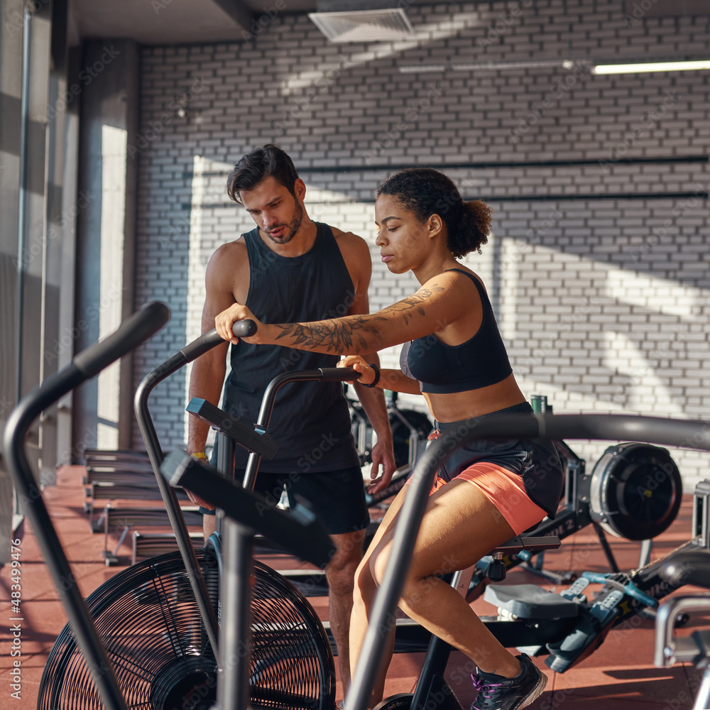 Obraz premium Trainer looking at orbitrek while woman exercising