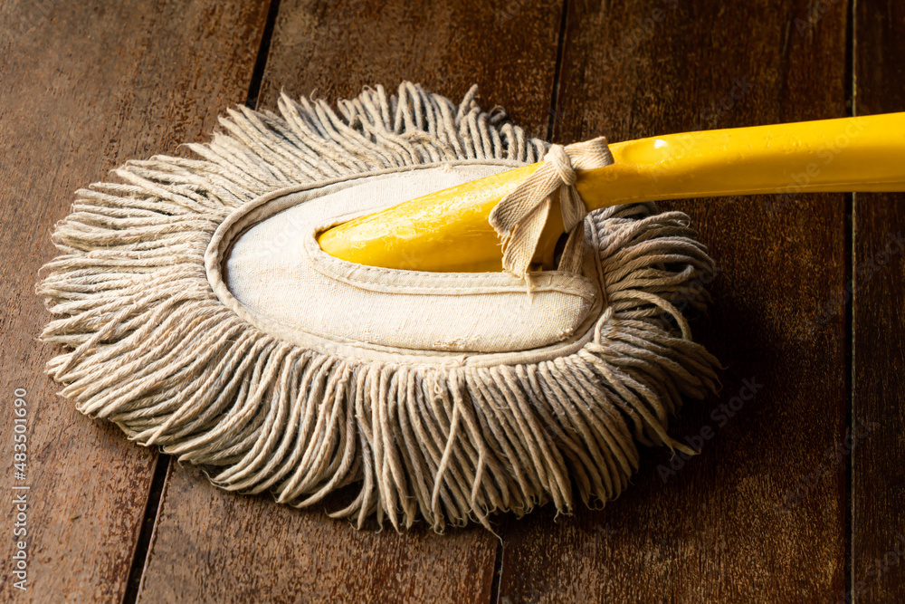 View of used handy mop on wooden floor. Handy mop is use to clean dust on  the office table. Stock Photo | Adobe Stock