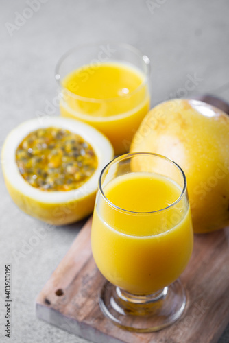 Glass with passion fruit juice and sliced ​​passion fruit on the table.