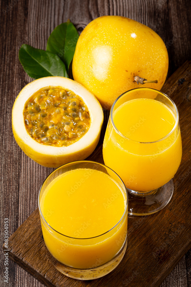 Glass with passion fruit juice and sliced passion fruit on the table. Glass with passion fruit juice and sliced passion fruit on the table.