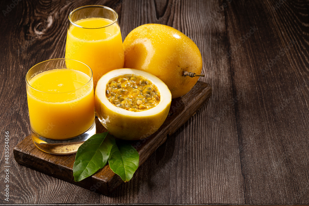 Glass with passion fruit juice and sliced passion fruit on the table. Glass with passion fruit juice and sliced passion fruit on the table.