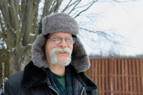 senior man in fur hat on winter day outside