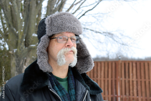 senior man in fur hat on winter day outside