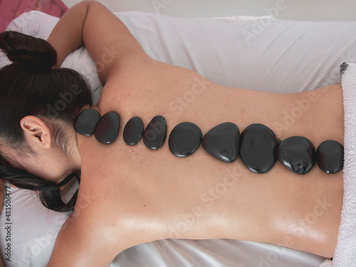 Mujer haciendo masaje terapia con piedras de calor en un salón de bellezas