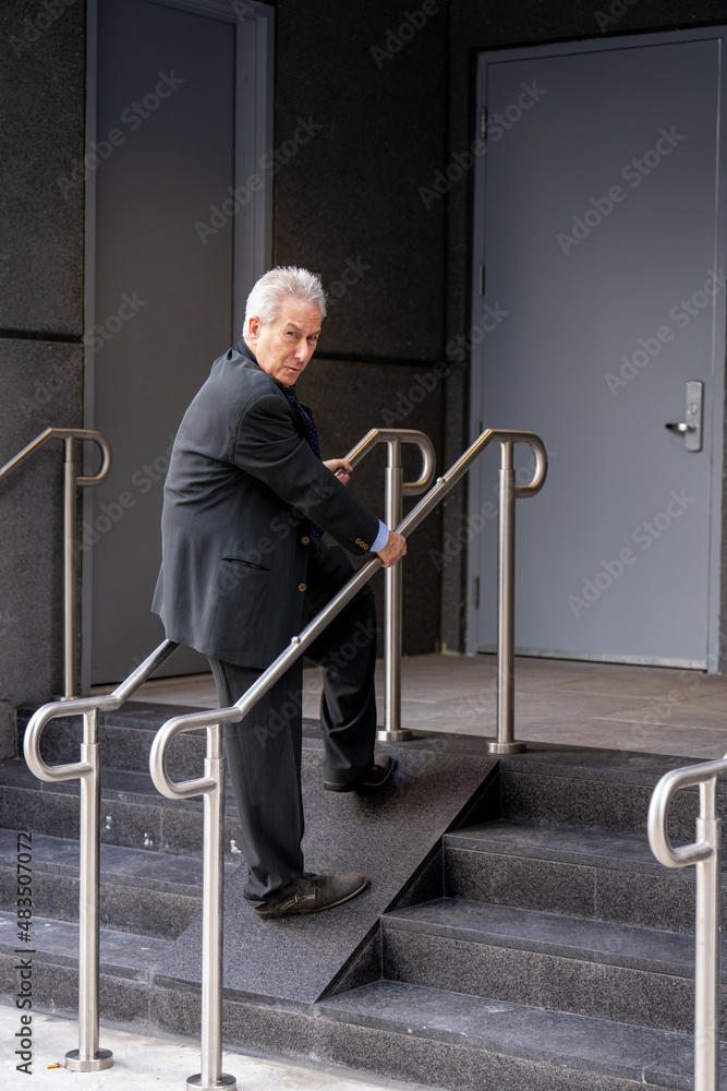 Businessman walking up a very narrow handicapped ramp to an office building