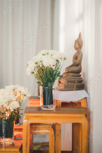 Buddha statue with flowers and white background