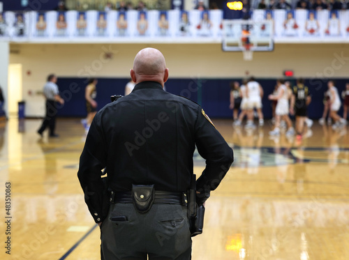 Canvas Print A police officer watches a high school basketball game