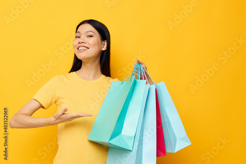Charming young Asian woman with packages in hands shopping isolated background unaltered
