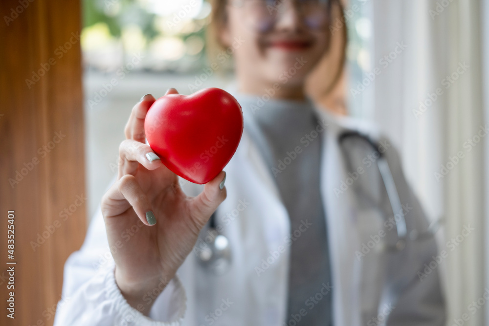 Smiling female doctor with stethoscope holding red heart shape in hand. Healthcare and medical concept. Smiling female doctor with stethoscope holding red heart shape in hand. Healthcare and medical concept.