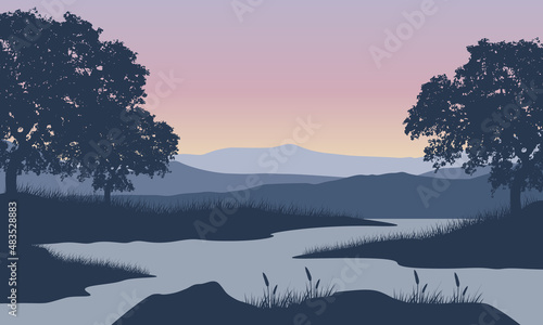 A view of the mountain view with an aesthetic silhouette of pine trees from the lakeside at sunrise