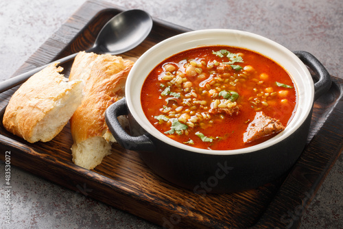 Traditional soup Chorba Frik made from lamb, Freekeh and vegetables close-up in a plate on the table. Horizontal