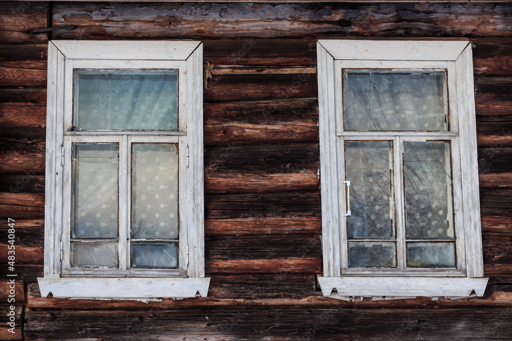 two wooden white windows with glass in a wooden log house. Background, splash screen. Tver, Russia.
