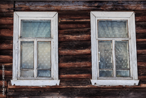 two wooden white windows with glass in a wooden log house. Background, splash screen. Tver, Russia.
