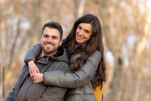 Young couple in love hugging in the park and looking at camera