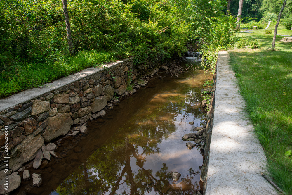 Stone canal with tranquil flowing water in green nature landscape Stone canal with tranquil flowing water in green nature landscape