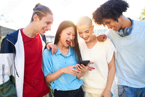  Gen Z young students using smartphone and social networks together. Multiracial people having fun together watching cell phone screens outdoors. © CarlosBarquero