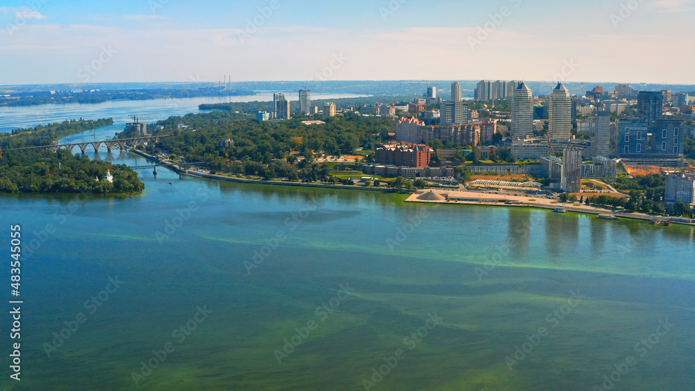 Fototapeta premium Beautiful urban environment on a summer day. Aerial view of the summer landscape with a view of the river and the city on the shore.
