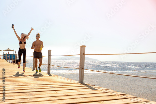 person walking on the beach.a girl and a guy run along the pier near the sea