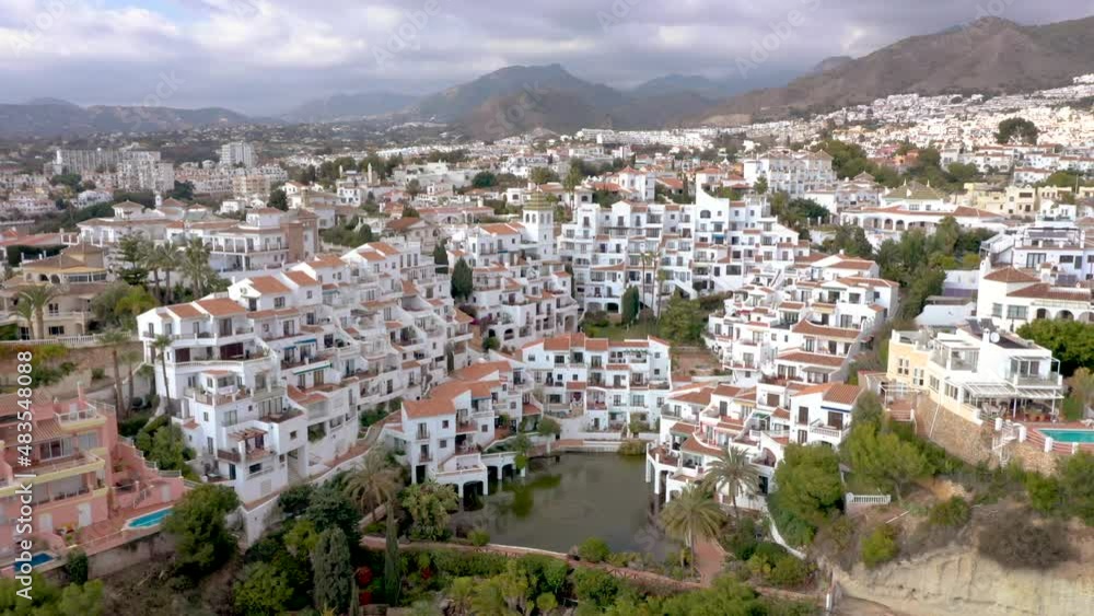 Beautiful and idyllic city of Nerja situated on Costa del Sol, Malaga, Spain. One of the most popular touristic attraction on Costa del Sol. Perspective from above. Drone backward. Cloudy sky Beautiful and idyllic city of Nerja situated on Costa del Sol, Malaga, Spain. One of the most popular touristic attraction on Costa del Sol. Perspective from above. Drone backward. Cloudy sky