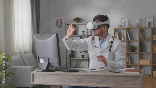 A male doctor in his office uses a 3D interface in virtual reality glasses