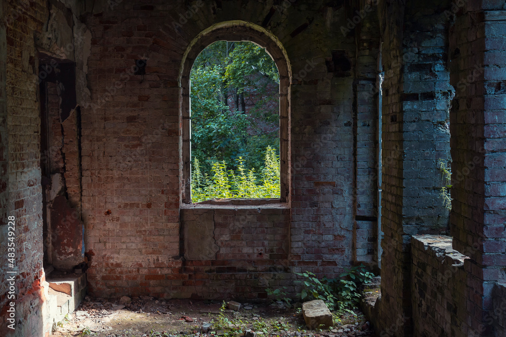 A window in a brick house ruins by summer day. Window view of an abandoned manor house