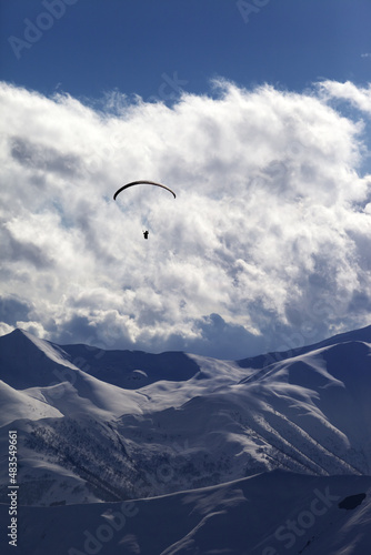 Winter mountain with clouds and silhouette of parachutist
