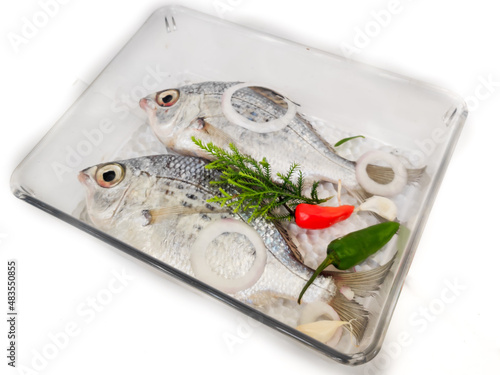 Gerres Fish (Gerres Filamentosus) Whipfin silver biddy Fish, Decorated with vegetables on a glass bowl, White Background.Selective Focus photo