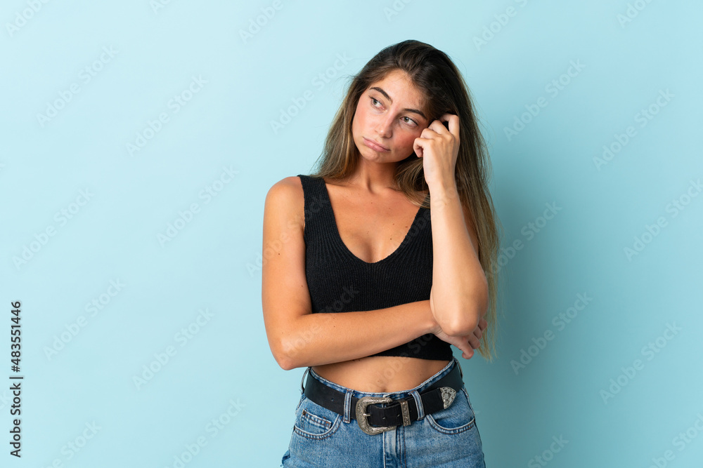 Young caucasian woman isolated on blue background with tired and bored expression Young caucasian woman isolated on blue background with tired and bored expression