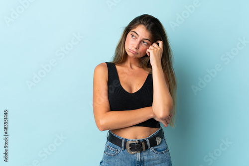 Young caucasian woman isolated on blue background with tired and bored expression