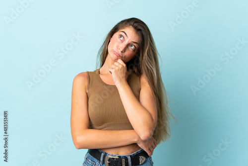 Young caucasian woman isolated on blue background and looking up
